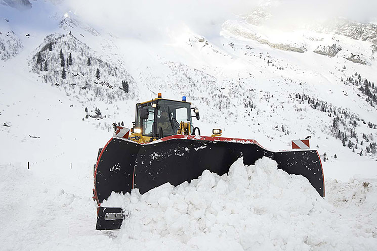 Engin équipé d'une lame tri-axiale en action dans la neige